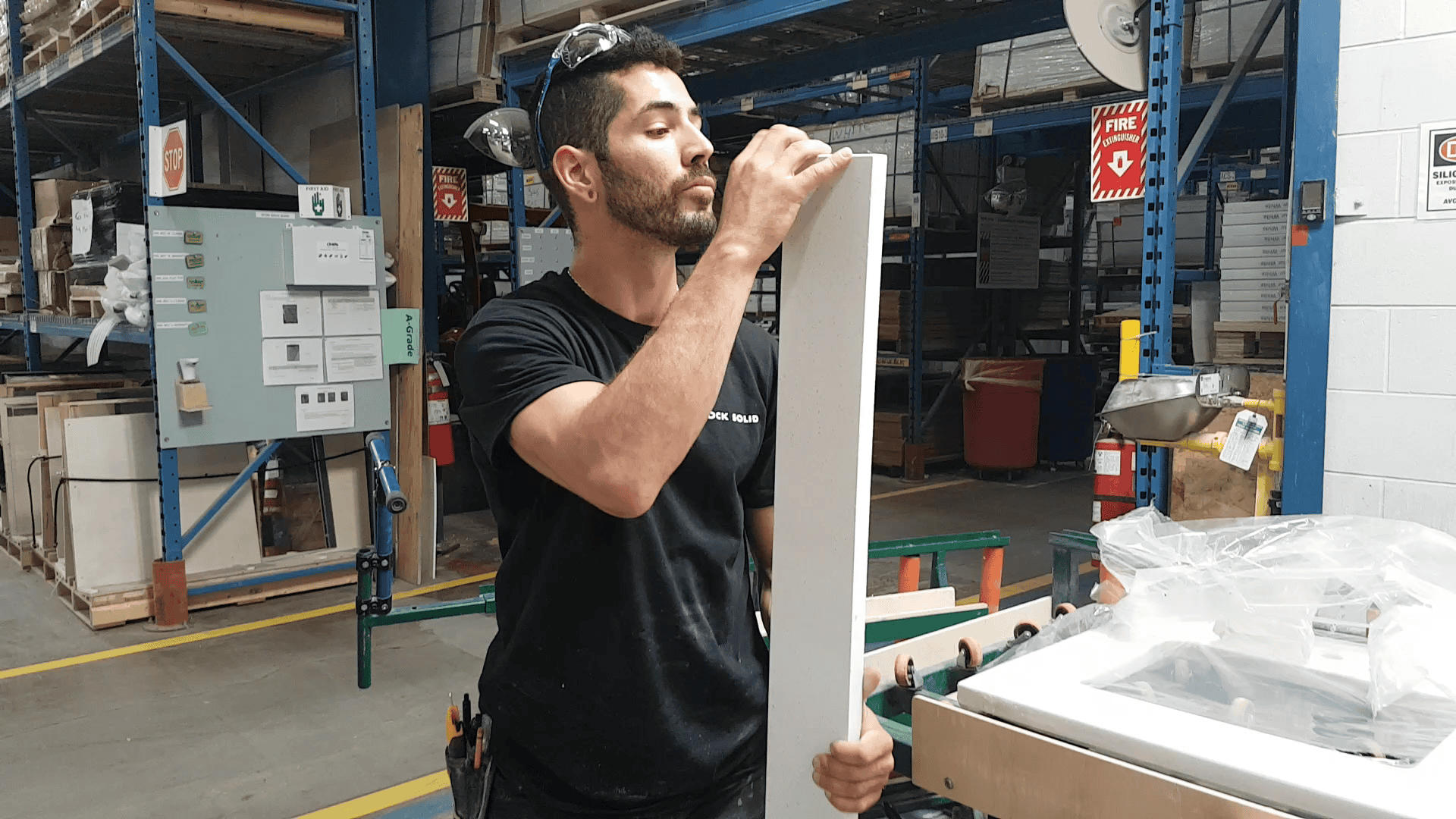 A Rock Solid team member inspects a quartz backsplash prior to packaging a vanity for shipping.